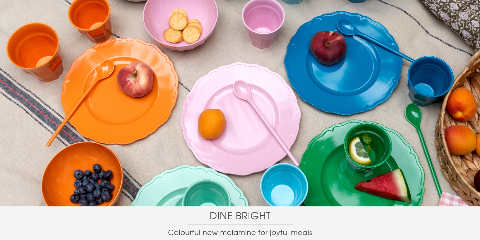 A blanket is covered with colourful plastic plates, bowls, spoons and beakers