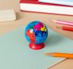 Colourful globe sharpener with a red base placed on a notebook