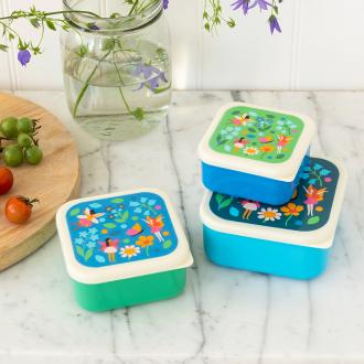 Three plastic snack boxes in blues greens and cream featuring prints of fairies amongst flowers