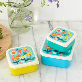 Three plastic snack boxes in yellow light blue turquoise and cream featuring prints of butterflies amongst flowers