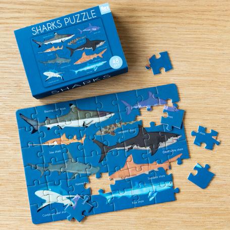 Small jigsaw puzzle with print of pictures of sharks being put together on table