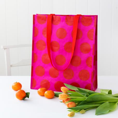 Recycled plastic shopping bag red circles pink background