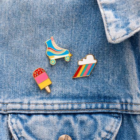 Roller skate, ice lolly and cloud burst pin badges attached to piece of clothing