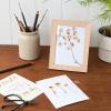 Wooden photo frame stood on table with pressed flowers on display